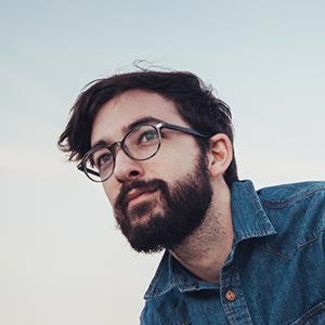 man outside with glasses looking away from camera