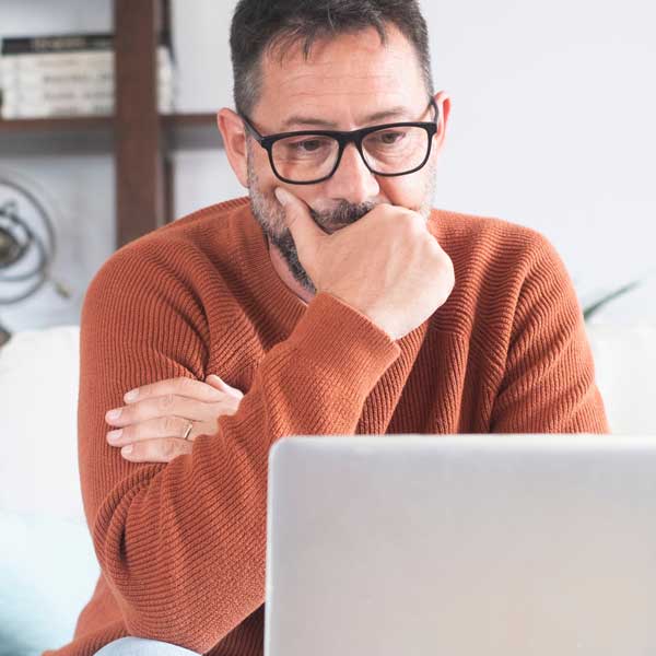man thinking on laptop