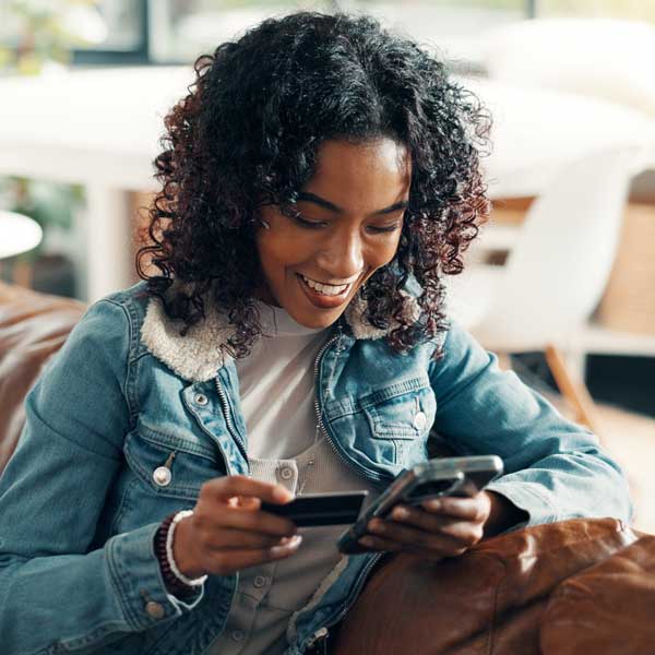 smiling woman with credit card looking at her smartphone, perhaps engaging in ecommerce